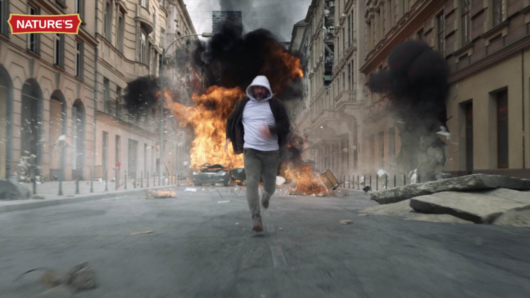 Man running from an explosion in a city street